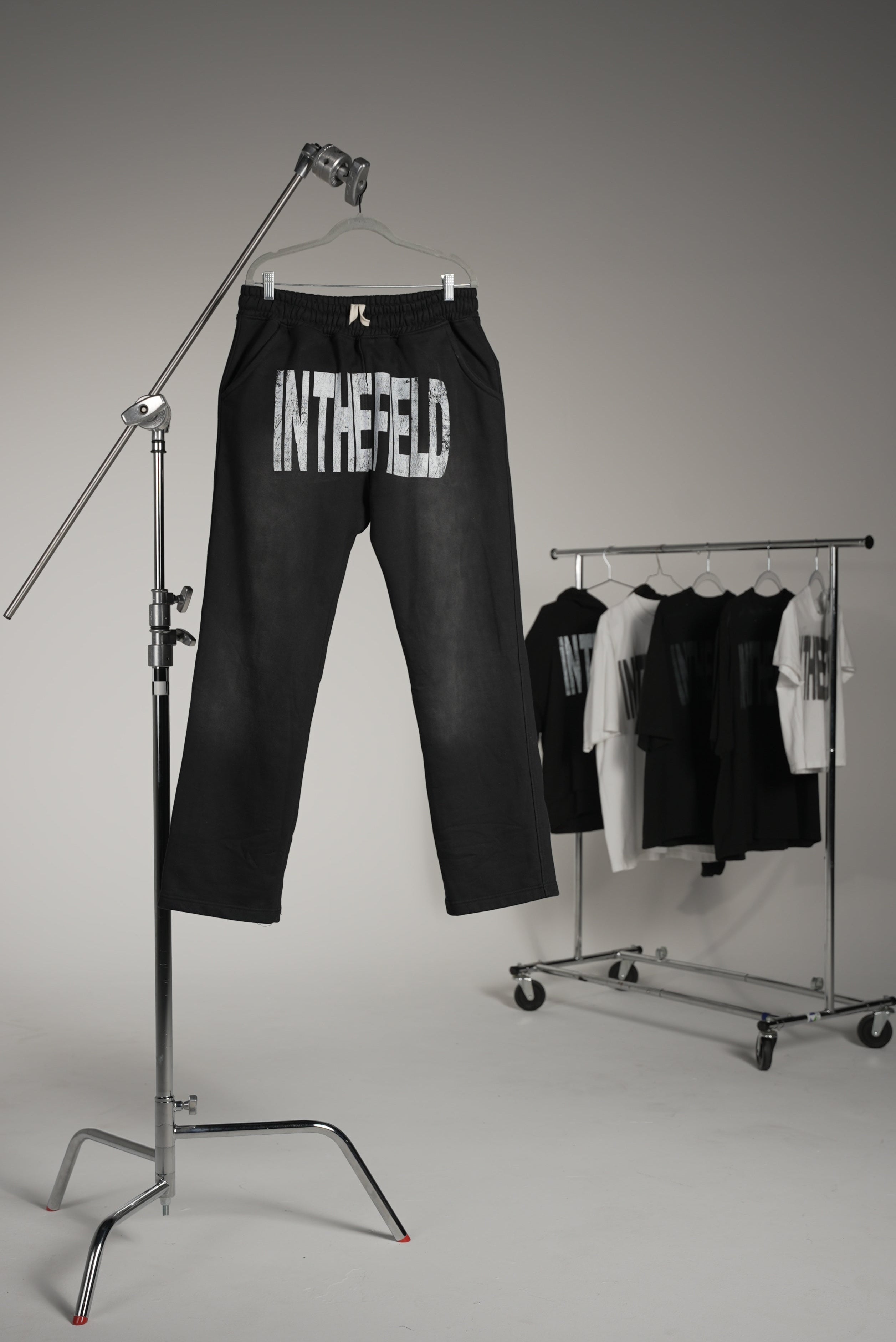 Black sweatpants with 'In The Field' branding on a white background. Industrial set. Set photoshoot